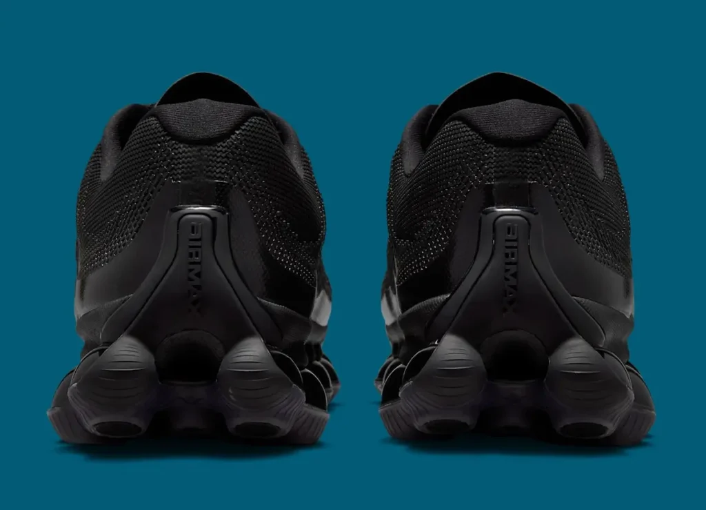 Rear view of Nike Air Liquid Max “Triple Black” shoe, highlighting the sculpted heel counter with embossed Air Max branding, textured mesh upper, and clustered point-loaded Air pods forming the heel cushioning system against a teal background