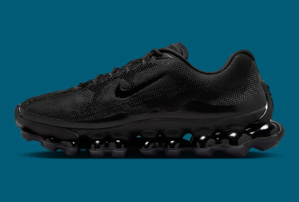 Lateral side view of Nike Air Liquid Max “Triple Black” shoe, featuring a tonal black textured mesh upper, subtle Swoosh, and a full-length point-loaded Air pod sole with glossy translucent cushioning against a teal background