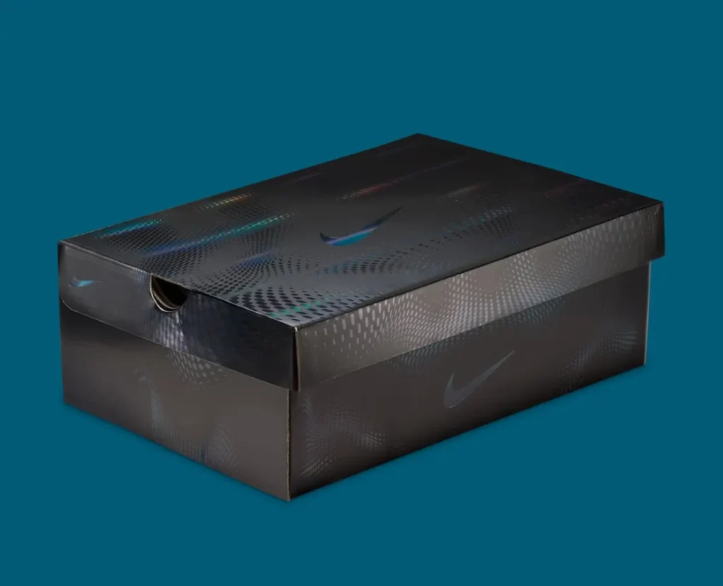 Nike Air Liquid Max “Triple Black” shoe box in matte black with iridescent dot-pattern graphics and subtle Swoosh branding, shown at an angled view against a teal background