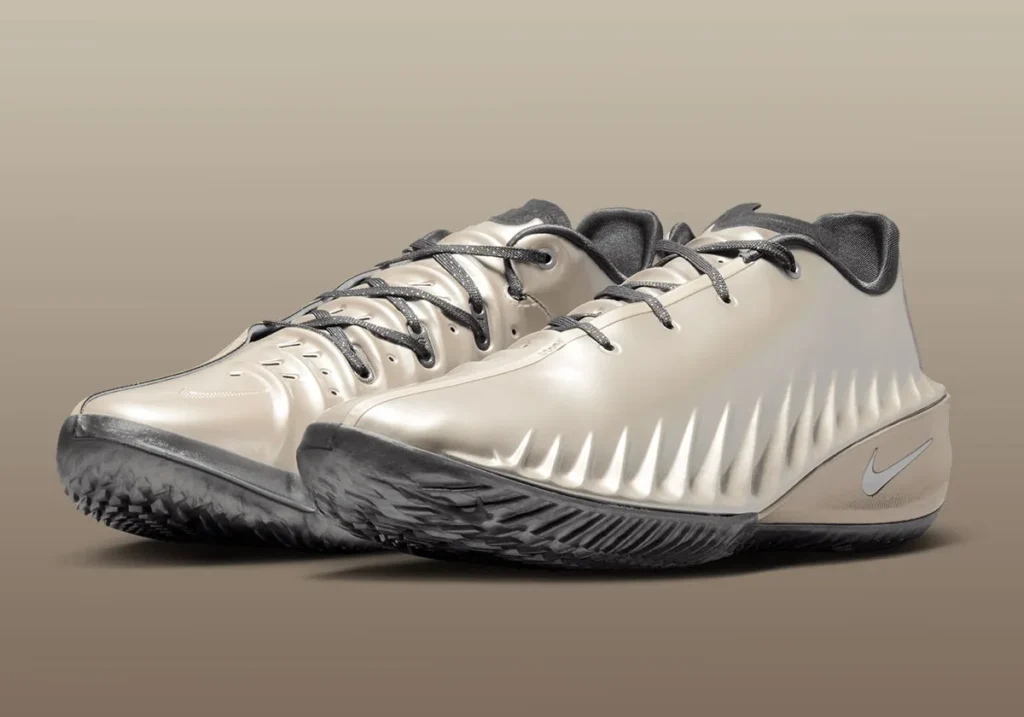 Three-quarter view of a pair of Nike low-top basketball shoes in a champagne-beige finish, featuring sculpted, ribbed uppers, dark gray laces, a streamlined midsole with subtle metallic sheen and Swoosh branding, and a smoky translucent outsole designed for grip and quick lateral movement
