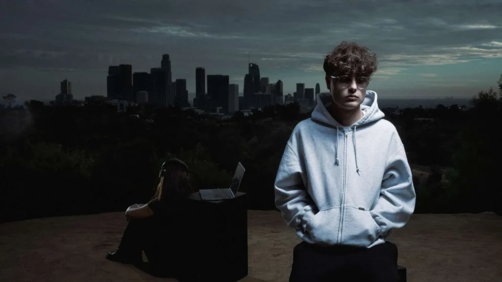 Noevdv stands in a minimalist grey hoodie overlooking the Los Angeles skyline at dusk, while a second figure sits with a laptop in ground, reinforcing the cinematic dual-world mood of “nobody like you” and its sped-up counterpart rollout