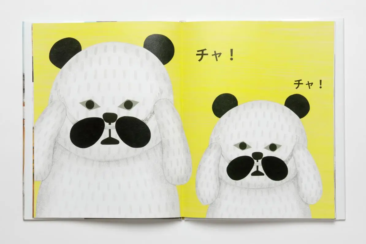 Open picture book spread featuring two stylized panda characters in a cut-paper illustration style, set against a bright yellow background with simple Japanese text, emphasizing playful shapes and minimal facial features