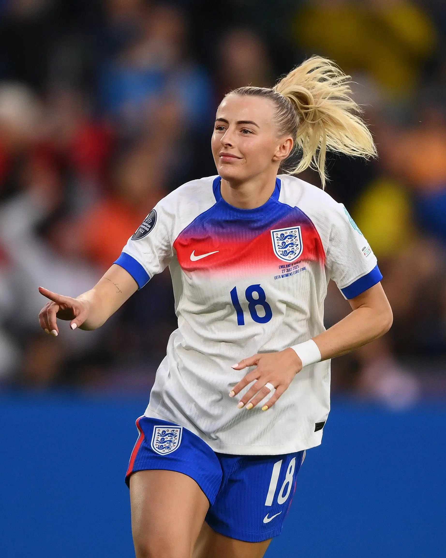 Chloe Kelly wearing England’s number 18 kit gestures while running during a UEFA Women’s Euro 2022 match, capturing a moment of post-goal movement and emotional release on the pitch