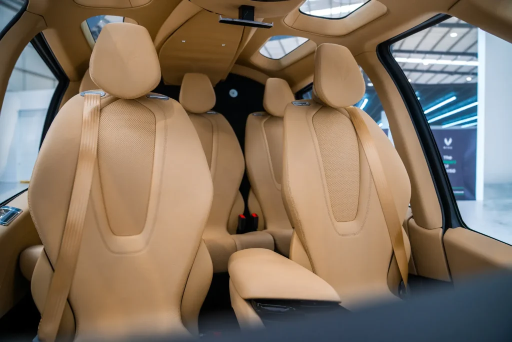 Interior view of a modern aircraft cabin with four beige leather seats, contoured headrests, and large windows, highlighting a clean, premium passenger layout