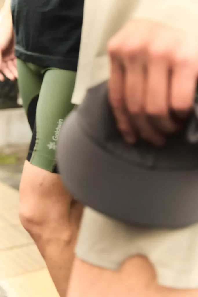 Dynamic close-up of runners in motion wearing lightweight technical athletic apparel, including olive compression shorts and neutral-toned performance layers, captured with soft motion blur during an outdoor group run