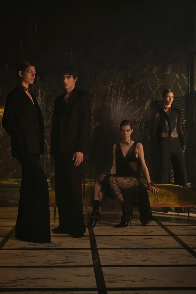 Group portrait featuring Fendi Cruise 2027 tailored black looks, sheer lace textures, elongated silhouettes, and gothic-inspired eveningwear against a dramatic marble backdrop