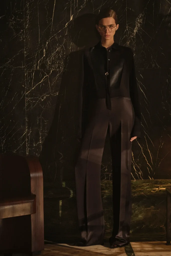 Model wearing oversized aviator glasses with a sharply tailored black Fendi ensemble, combining fluid wide-leg trousers with sleek leather panel detailing