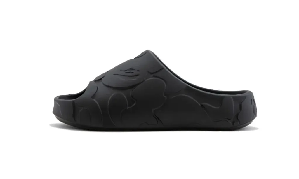 Side profile of a black BAPE STA slide featuring molded construction, tonal camouflage embossing, and a streamlined open-back silhouette