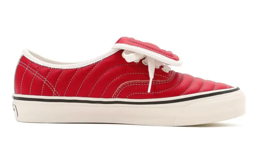Lateral side view of a red leather Vans shoe highlighting padded quilting, view white stitching lines, oversized tongue detail, and retro-inspired cream sole