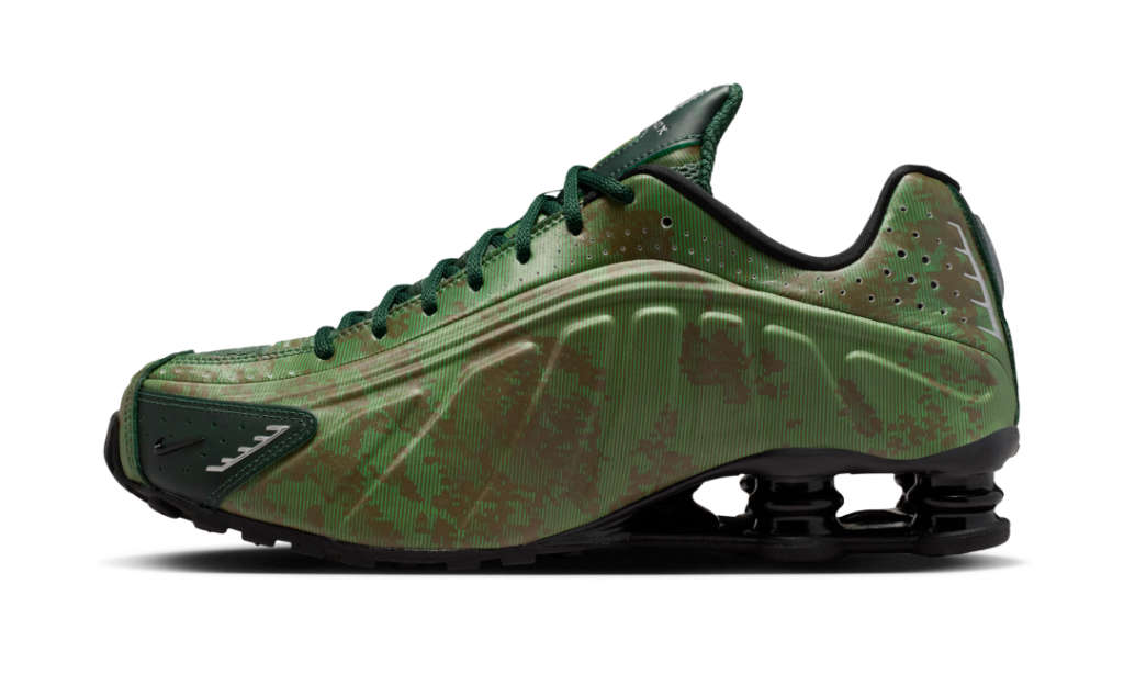 Side profile of the Nike Shox R4 “Noble Green/Team Kelly Green” highlighting the sculpted upper, tonal green linear patterning, perforated collar detailing, and signature black mechanical Shox cushion