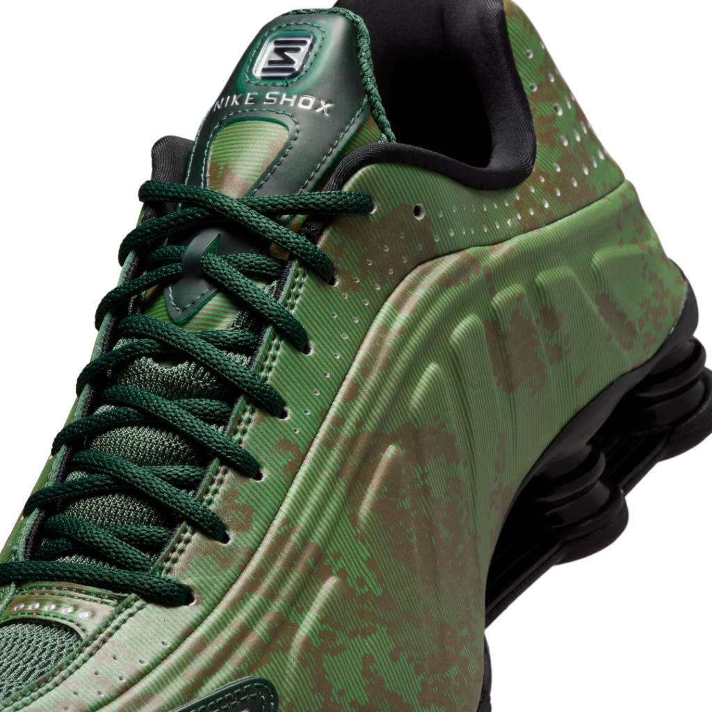 Side profile of the Nike Shox R4 “Noble Green/Team Kelly Green” highlighting the sculpted upper, tonal green linear patterning, perforated collar detailing, and signature black mechanical Shox cushion