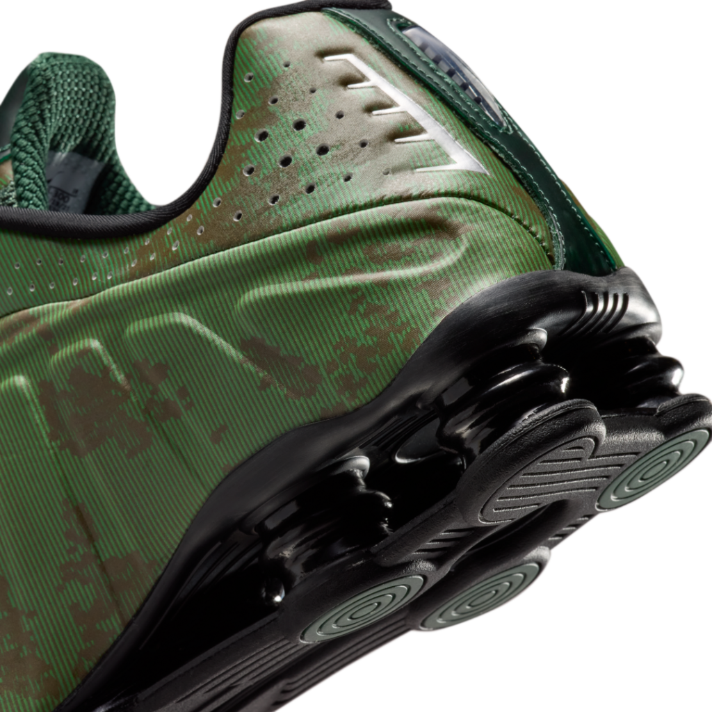 Detailed close-up of the Nike Shox R4 heel featuring glossy black Shox columns, layered green upper textures, and sculpted cushioning architecture designed for a futuristic Y2K aesthetic
