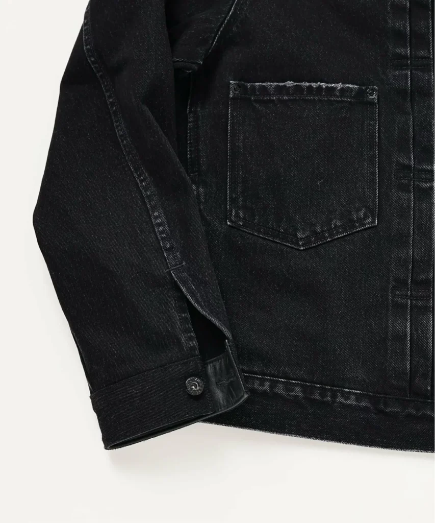 Close-up of the jacket sleeve and cuff construction, showcasing premium denim fabric, tonal hardware, and meticulous stitch