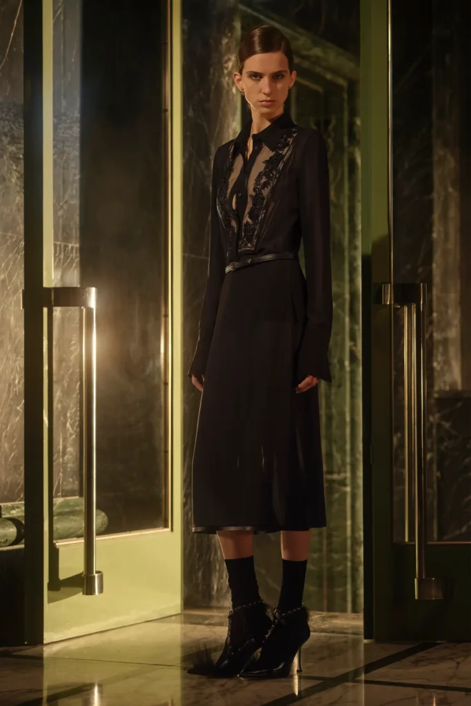 Sheer black lace Fendi midi dress with delicate embroidery details, styled with pointed heels and dramatic lighting in a refined architectural setting
