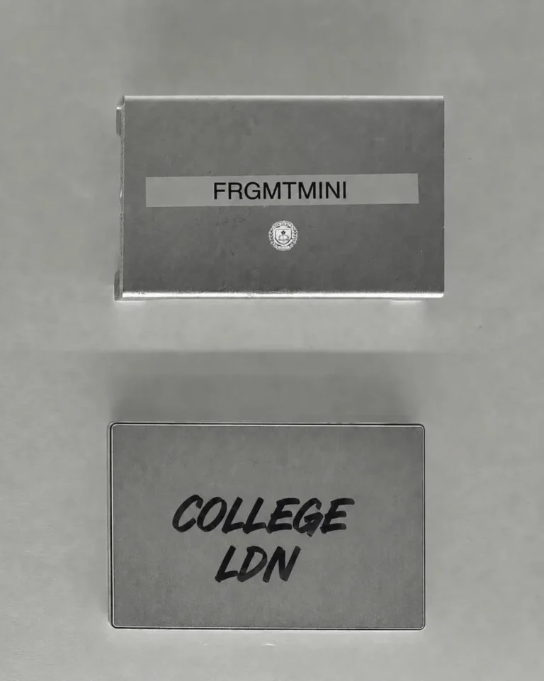 Minimal campaign teaser image for frgmtmini’s Spring/Summer 2026 “College” collection featuring monochromatic packaging and printed branding. A silver-grey box marked “FRGMTMINI” appears above a matching card reading “COLLEGE LDN” in handwritten-style lettering, paired with a small academic crest motif. The clean composition and restrained graphic language reflect Hiroshi Fujiwara’s signature minimalist aesthetic while referencing collegiate identity, archival design codes and understated streetwear culture
