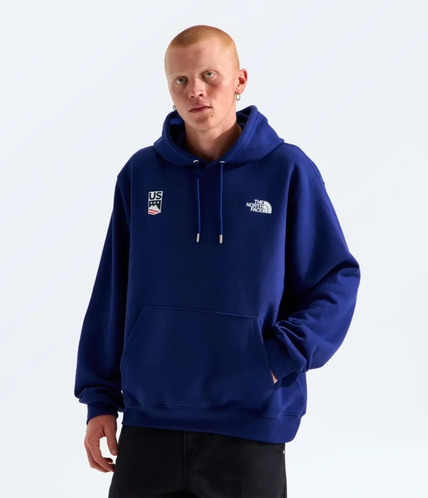 Model wearing a royal blue oversized Team USA hoodie by The North Face with minimalist chest branding and official U.S. Ski & Snowboard insignia in a clean studio setting