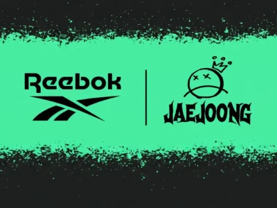 Promotional teaser graphic for a collaboration between Reebok and Kim Jaejoong. The design features a bold mint-green horizontal band across a distressed black background with paint-splatter textures. On the left sits the Reebok wordmark and vector logo in black; on the right appears the “JAEJOONG” logo in jagged gothic lettering beneath a hand-drawn crowned face icon with X-shaped eyes. The overall aesthetic feels dark, rebellious, and streetwear-oriented with punk and underground fashion influence