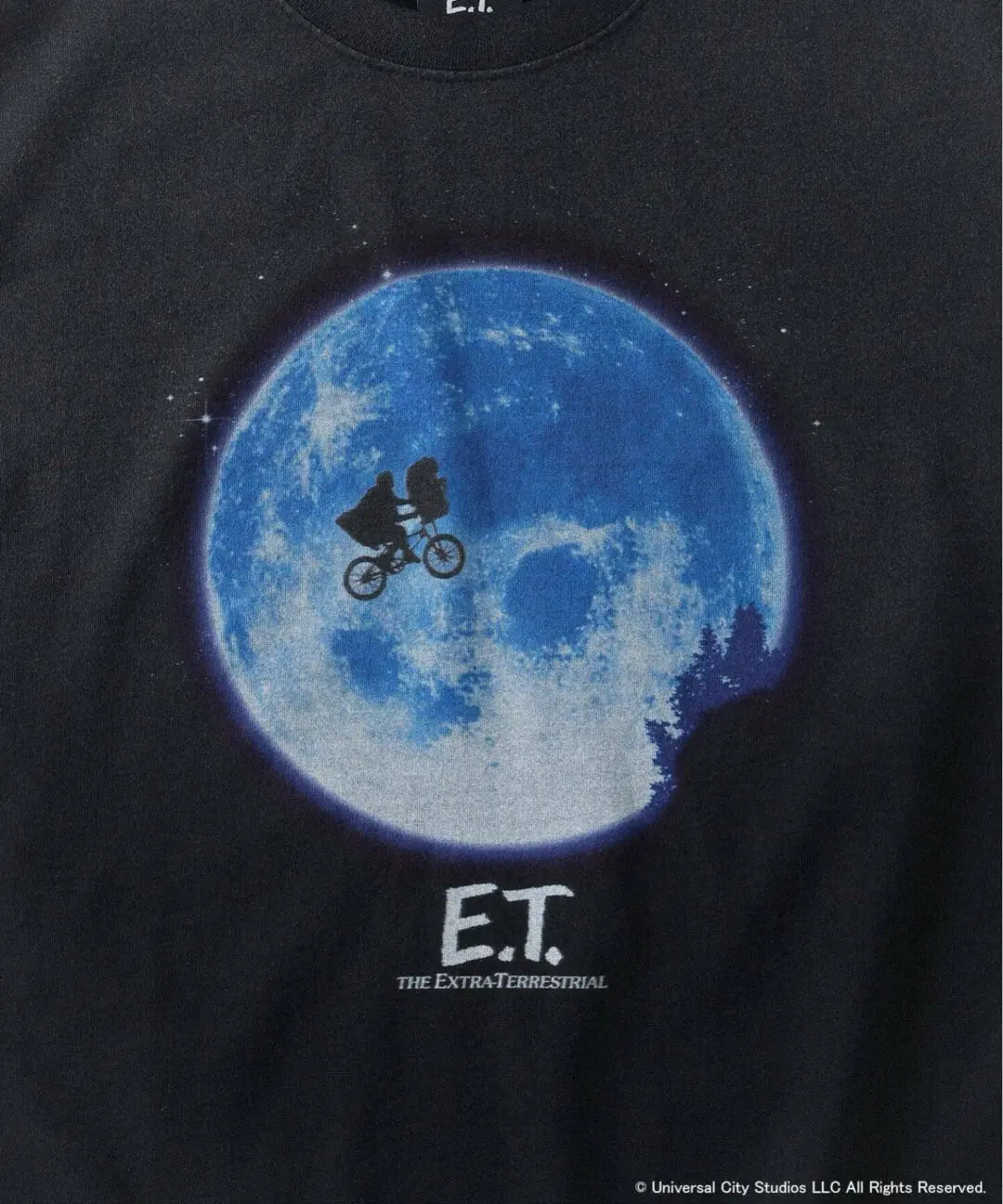 Close-up of black E.T. graphic T-shirt featuring the iconic bicycle silhouette flying across a luminous blue moon with E.T. The Extra-Terrestrial logo beneath