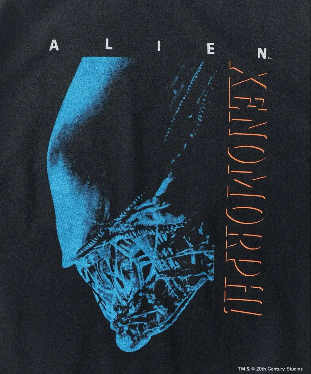 Close-up of black Alien graphic T-shirt featuring a blue Xenomorph head illustration paired with spaced typography and vertical orange “Xenomorph” lettering