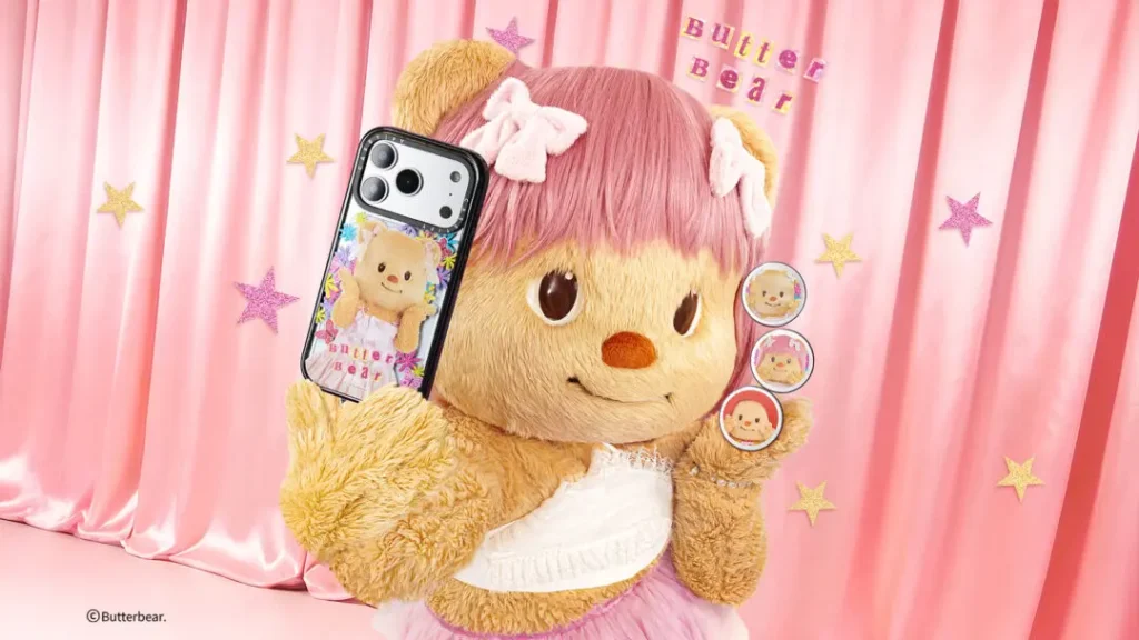 Butterbear mascot with pink hair bows poses in front of pastel pink curtains while showcasing CASETiFY floral phone cases and collectible grip accessories decorated with playful character artwork and sparkling star details
