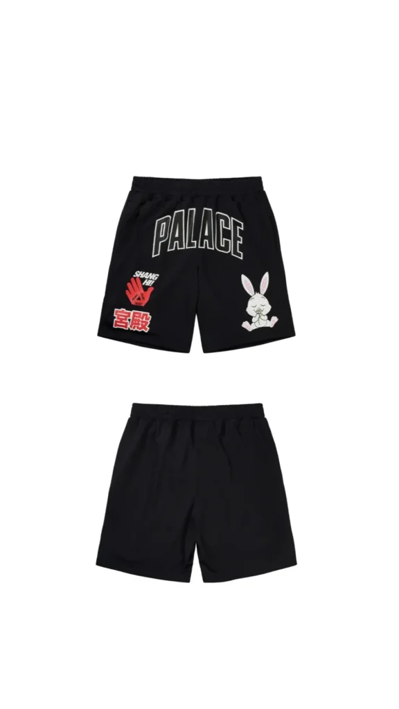 Front and back views of black Palace athletic shorts featuring oversized outlined “PALACE” lettering across the front, a red “SHANG HI!” hand graphic incorporating the Tri-Ferg logo, red Chinese character detailing, and a seated cartoon rabbit mascot. The reverse remains minimal in solid black, extending the playful sport-inspired visual language of the Shanghai flagship collection
