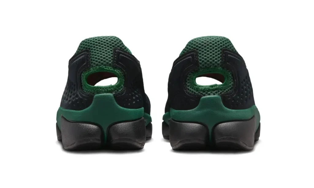 Rear view of a pair of dark green and black Nike slip-on sneakers featuring perforated molded uppers, open heel cutout detailing, breathable green mesh collar panels, and sculpted chunky heel units against a clean light gray studio background