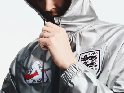 Model wearing a reflective silver Palace x Nike England hooded jacket with co-branded Palace and Nike logo patch, England crest, and metallic technical finish
