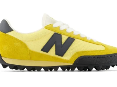 Side profile of the New Balance Gator Run U GTR 9SR “Apollo Gold/Black” shoe featuring textured yellow hairy suede overlays, pale yellow mesh underlays, oversized black “N” branding, white rope laces, and a rugged pyramid-style rubber outsole inspired by the original 1982 turf traction design
