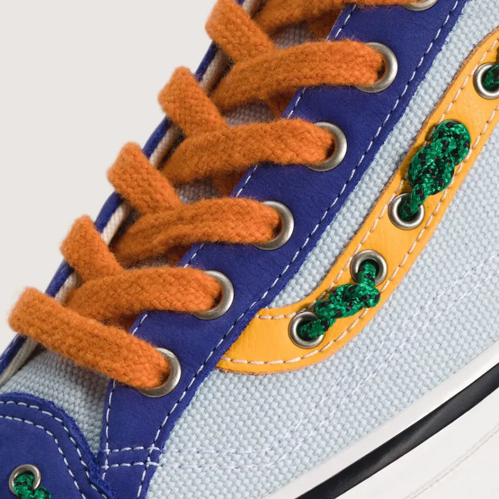 Close-up detail of the OTW by Vans Old Skool 36 “Knot” in the Royal Cobalt / Multi Blue colorway, highlighting fuzzy orange laces, vivid cobalt suede overlays, heavyweight light blue canvas, and nautical-inspired green rope knots threaded through metal eyelets along the reworked side stripe. The macro composition emphasizes texture contrast, color blocking, and the collection’s handcrafted maritime aesthetic