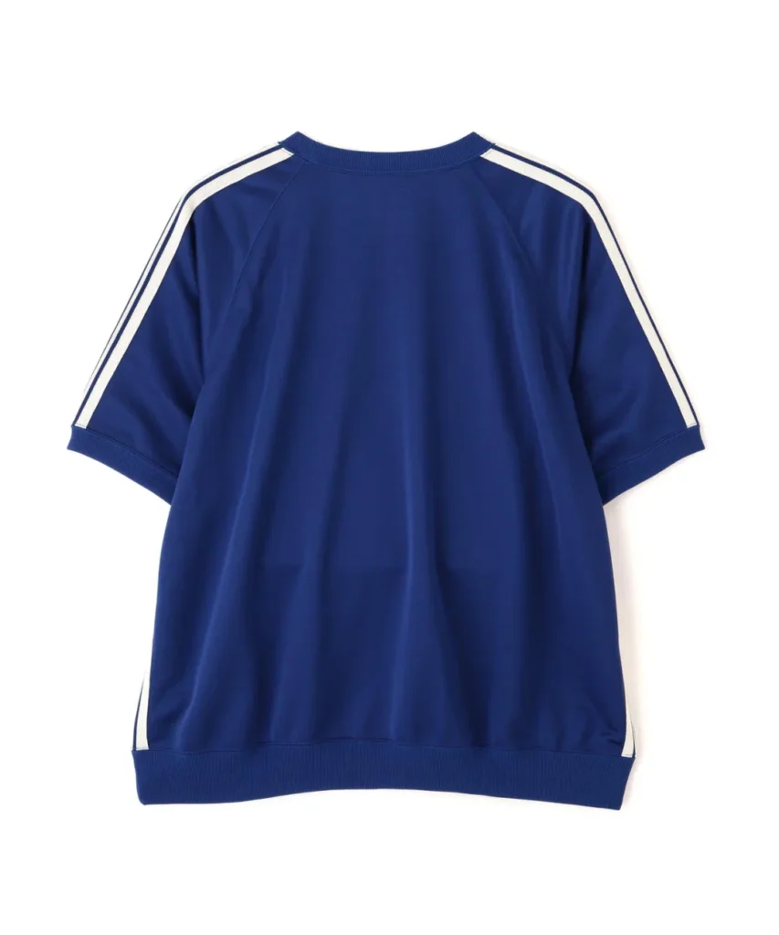 same Rear product view of the NEEDLES “Track S/S Crew Neck Shirt – Poly Smooth” in a saturated royal blue finish with contrasting white athletic striping along the raglan sleeves. The clean back profile highlights the relaxed oversized silhouette, ribbed hem detailing, and smooth technical fabric construction that define the label’s elevated interpretation of vintage sportswear