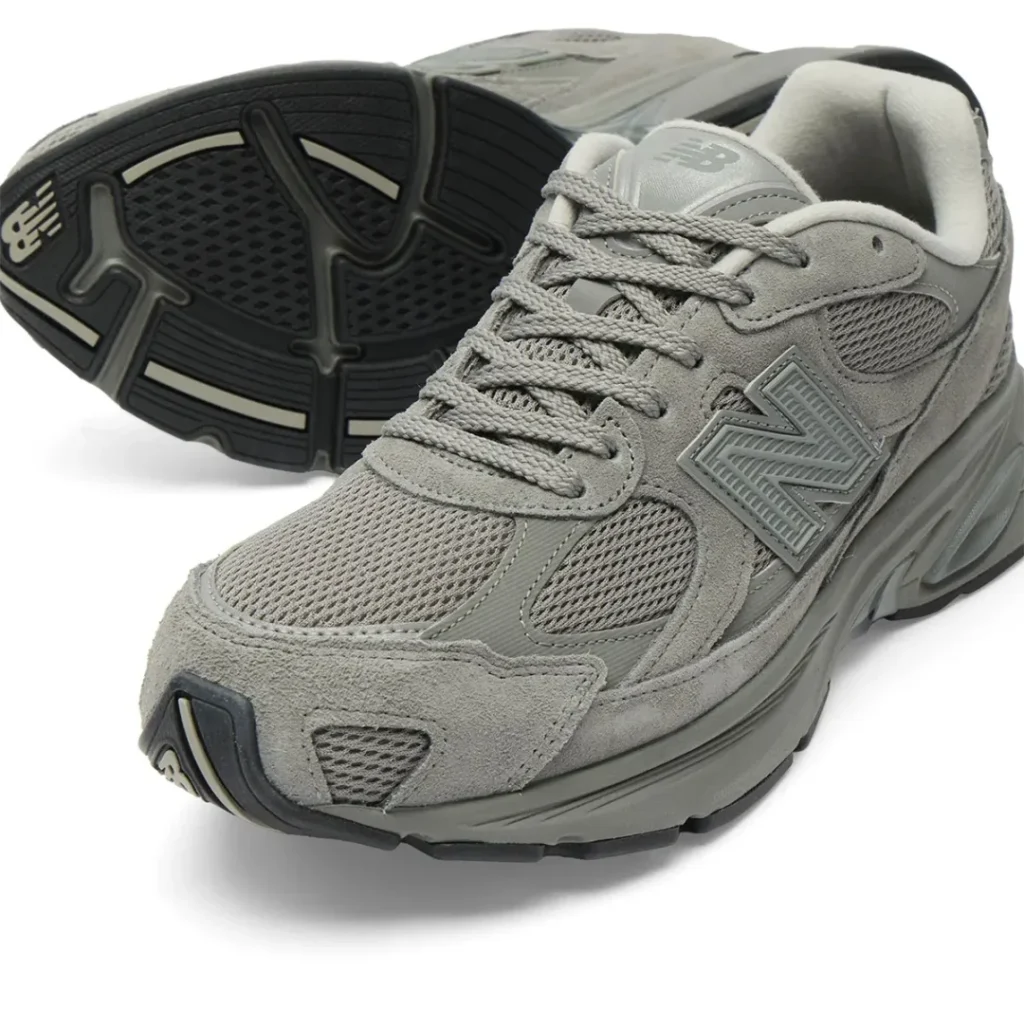 A closer angled view of the New Balance U2010 3EJ “Harbor Grey” emphasizes the shoe layered construction, showcasing breathable mesh panels wrapped in soft suede overlays and tonal synthetic detailing. The oversized grey “N” logo integrates seamlessly into the upper, while the sculpted ABZORB midsole and segmented black outsole reveal the silhouette’s balance of retro running performance and contemporary lifestyle cushioning. From the textured toe box to the pod-like heel geometry, the design delivers a quiet, utilitarian sophistication rooted in New Balance’s signature approach to tonal footwear