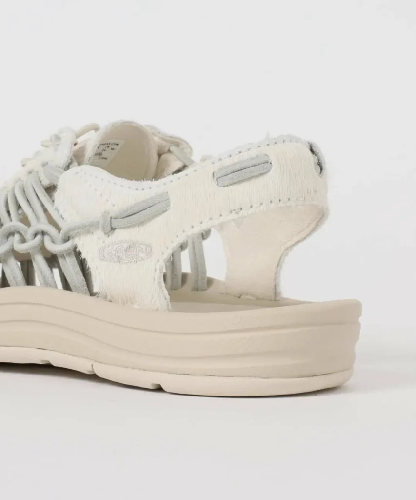 Close-up detail of the sandal’s rear quarter showing textured hairy leather finish, subtle embroidered KEEN branding, exposed heel opening, and cushioned platform sole
