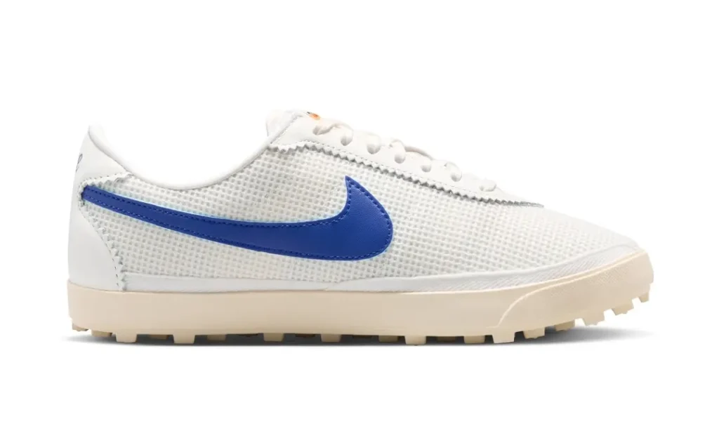 Profile view of a white mesh Nike shoe accented by a vibrant royal blue Swoosh, vintage cream midsole, and low-cut waffle outsole, channeling archival running design through a lightweight contemporary silhouette