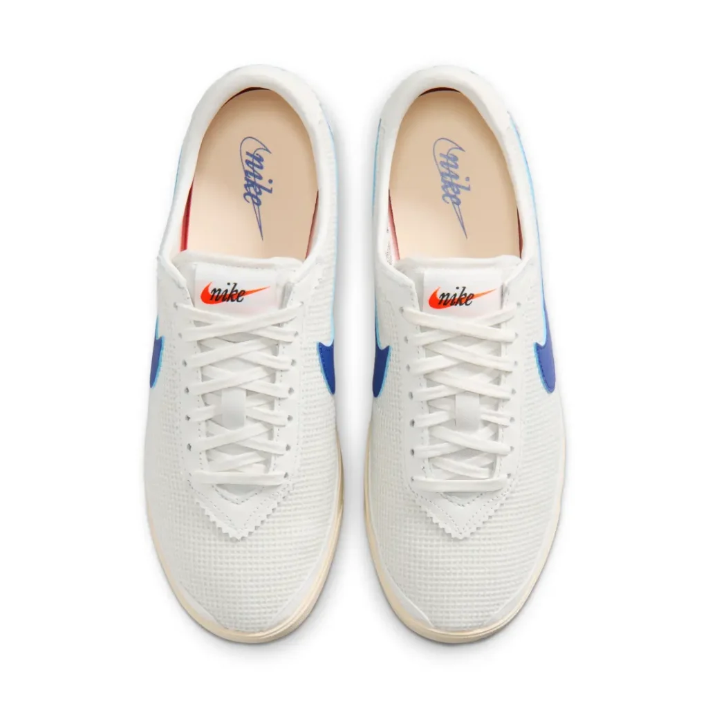 Top-down view of the white mesh Nike shoe showcasing clean tonal laces, royal blue side Swooshes, vintage cream insoles with retro script branding, and a streamlined low-profile runner silhouette