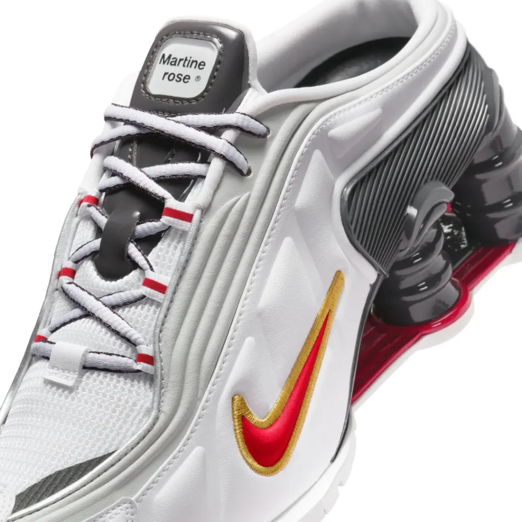Close-up of the Martine Rose x Nike Shox MR4 Mule highlighting premium white materials, embroidered red-and-gold Nike Swoosh, layered panel construction, and co-branded tongue