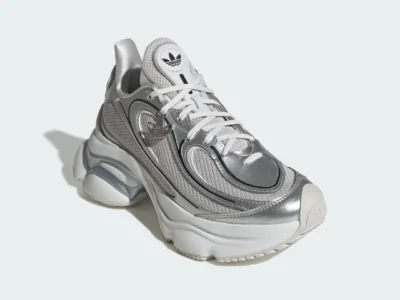 Three-quarter front view of the adidas OZVENUZ in Silver Metallic, highlighting its futuristic Y2K-inspired silhouette, oversized sole unit, and flowing metallic accent