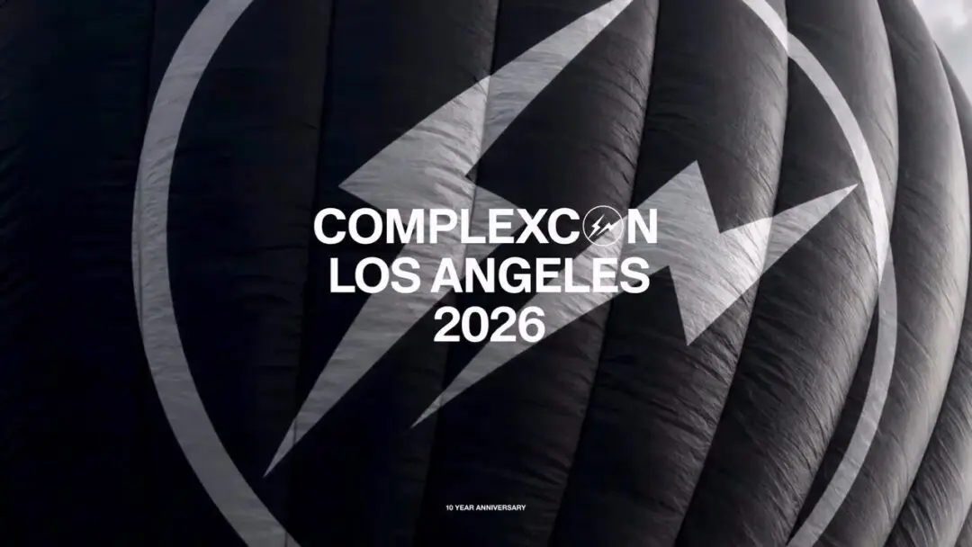 Extreme close-up campaign image of a matte-black hot air balloon surface featuring an oversized Fragment lightning-bolt emblem enclosed within a circular mark. Centered white typography announces “COMPLEXCON LOS ANGELES 2026,” while a subtle “10 YEAR ANNIVERSARY” detail anchors the composition below. The tight crop emphasizes texture, scale, and graphic identity, creating a minimal yet cinematic view language that blends streetwear symbolism, luxury restraint, and event-world anticipation