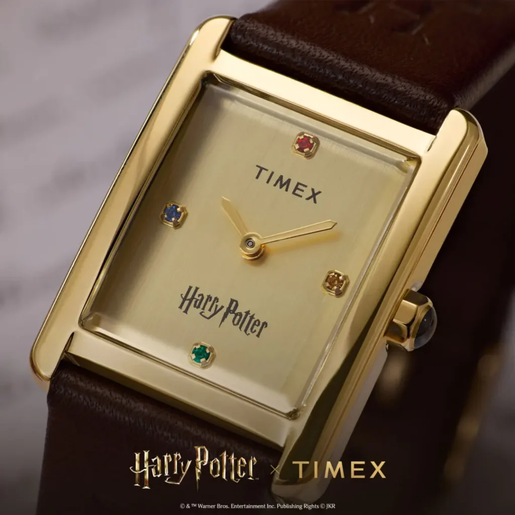 Close-up campaign image of the Timex x Harry Potter and the Philosopher's Stone Hailey Hogwarts watch featuring a rectangular gold-tone case, brushed champagne dial, minimalist gold hands, four house-colored crystal hour markers, and dark brown leather strap with refined vintage-inspired style