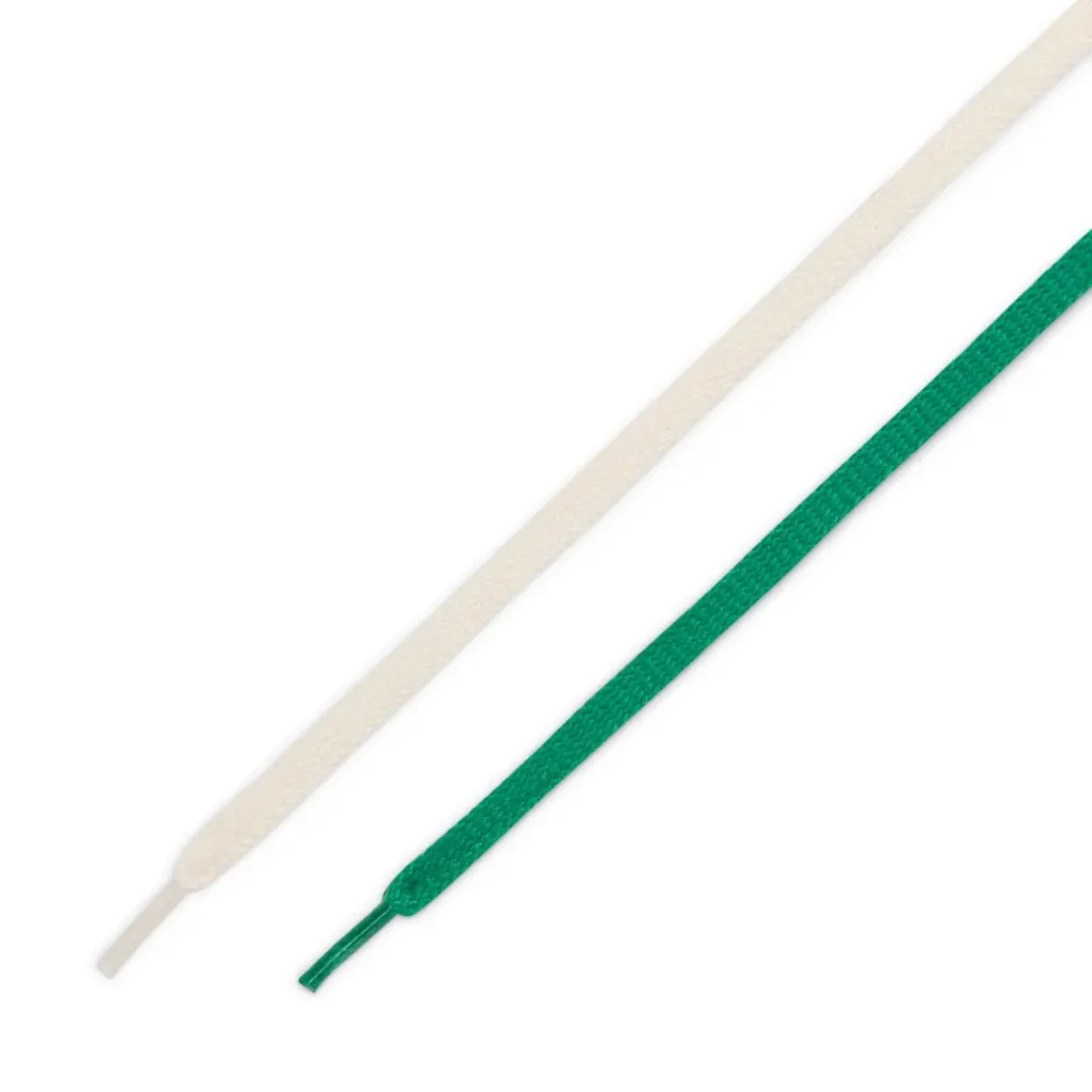 Close-up image of the interchangeable lace set included with the emerald green Nike Cortez-inspired turf shoe, featuring one cream-colored lace and one tonal green lace against a clean light grey background. The alternate lace options reinforce the shoe’s retro athletic styling and customizable vintage football aesthetic
