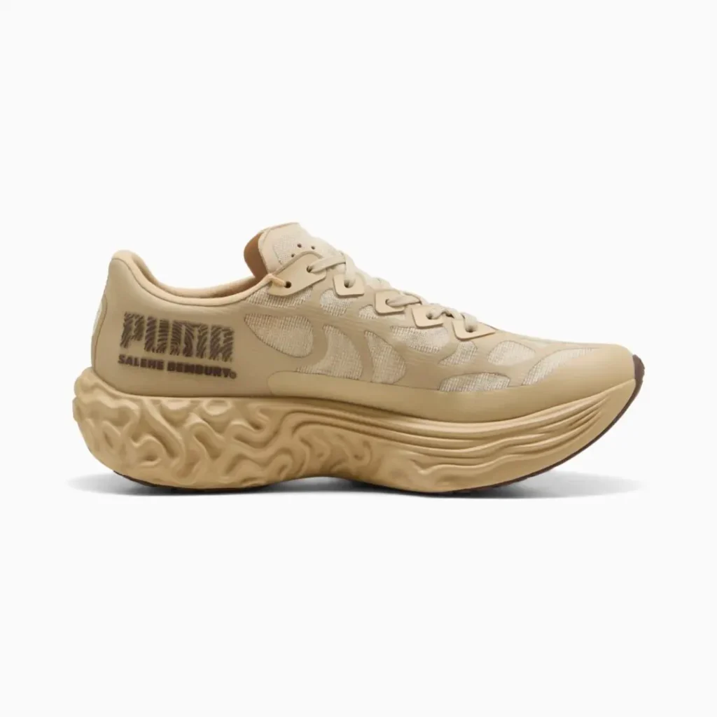 Medial side view of the cream-toned sneaker featuring textured mesh underlays, tonal overlays, heel branding details, and a deeply sculpted foam midsole