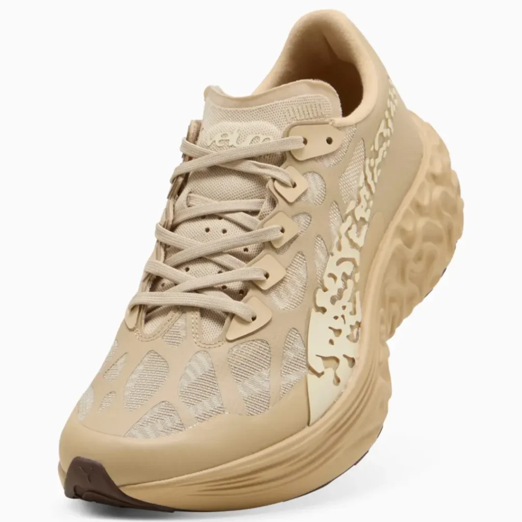 Angled front view of the sneaker emphasizing layered lacing, technical woven upper, organic sidewall cutouts, and a chunky show-focused sole unit