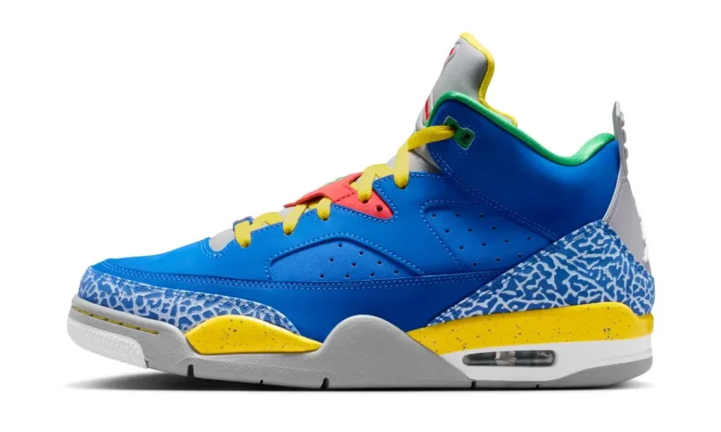 Side-profile product image of a vibrant basketball shoe set against a clean light gray background. The shoe features a saturated royal blue leather upper paired with yellow laces and a matching speckled yellow midsole accent. Blue elephant-print overlays wrap around the toe and heel, contrasted by coral-red eyelet detailing, green inner lining, and a gray tongue with red branding. A sculpted gray-and-white sole with visible air cushioning gives the silhouette a retro performance look while the bold color blocking adds a playl, street-inspired character