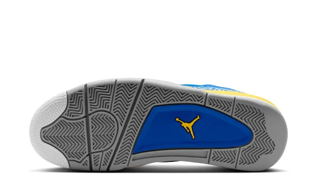 Outsole view of a retro-inspired basketball shoe shown against a light gray background. The sole features layered gray rubber with varied herringbone traction patterns across the forefoot and heel for a textured, geometric look. At the center, a glossy royal blue midfoot panel is accented by a contrasting yellow logo mark, adding a vivid pop of color beneath the otherwise neutral base. The design balances classic court performance details with play high-contrast style