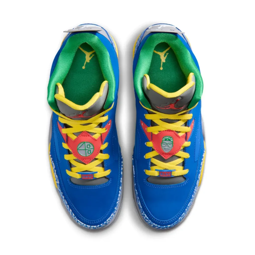 Top-down product view of a colorful retro basketball sneaker pair arranged symmetrically against a light gray background. The design features vivid royal blue uppers with bright yellow laces, green padded lining, and gray tongues finished with red embroidered logo details. Coral-red lace panels at the center introduce graphic badge-style accents, while blue elephant-print trim appears along the lower edges. Additional small decorative labels and contrasting interior branding give the shoes a playful, collectible feel rooted in expressive basketball and street-culture aesthetics