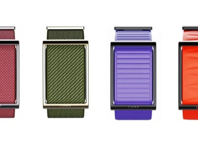 Four colorways of the Luna Band displayed front-on against a light background, showcasing the screenless fitness tracker’s minimalist rectangular body and textured woven straps in burgundy, olive green, violet, and bright orange finishes