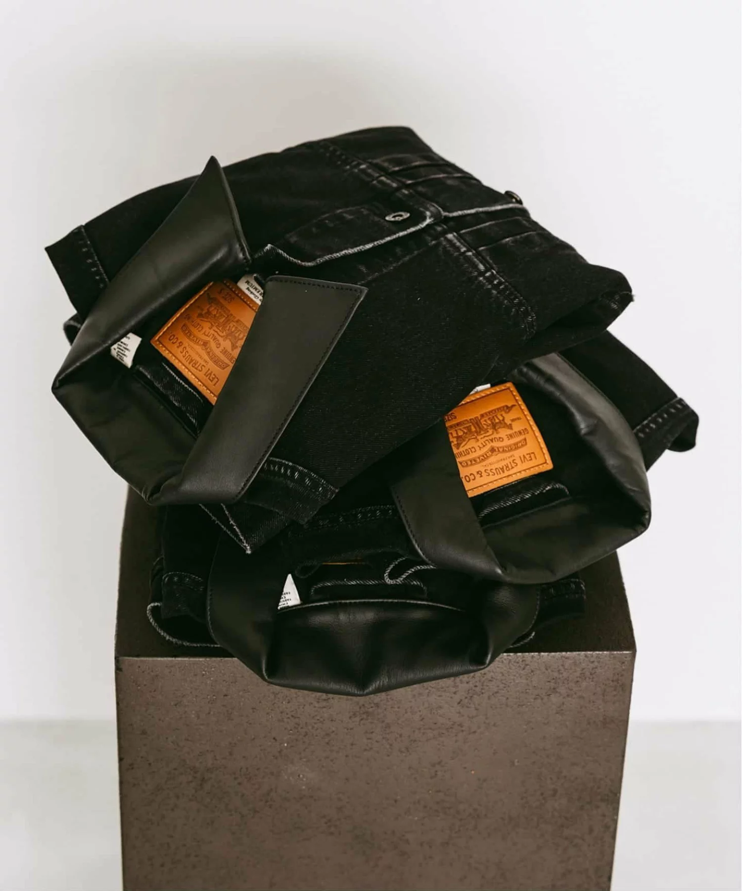Folded ÉDIFICE x Levi’s denim jackets stacked on a display pedestal, showcasing premium leather collar accents and archival-inspired craftsman
