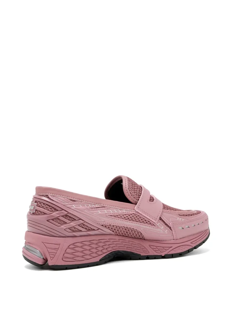 Side profile of the New Balance 1906L “Rose Sugar” loafer shoe in monochromatic dusty pink, featuring breathable mesh underlays, glossy synthetic overlays, penny-loafer strap detailing, and a chunky performance running sole with black outsole accents