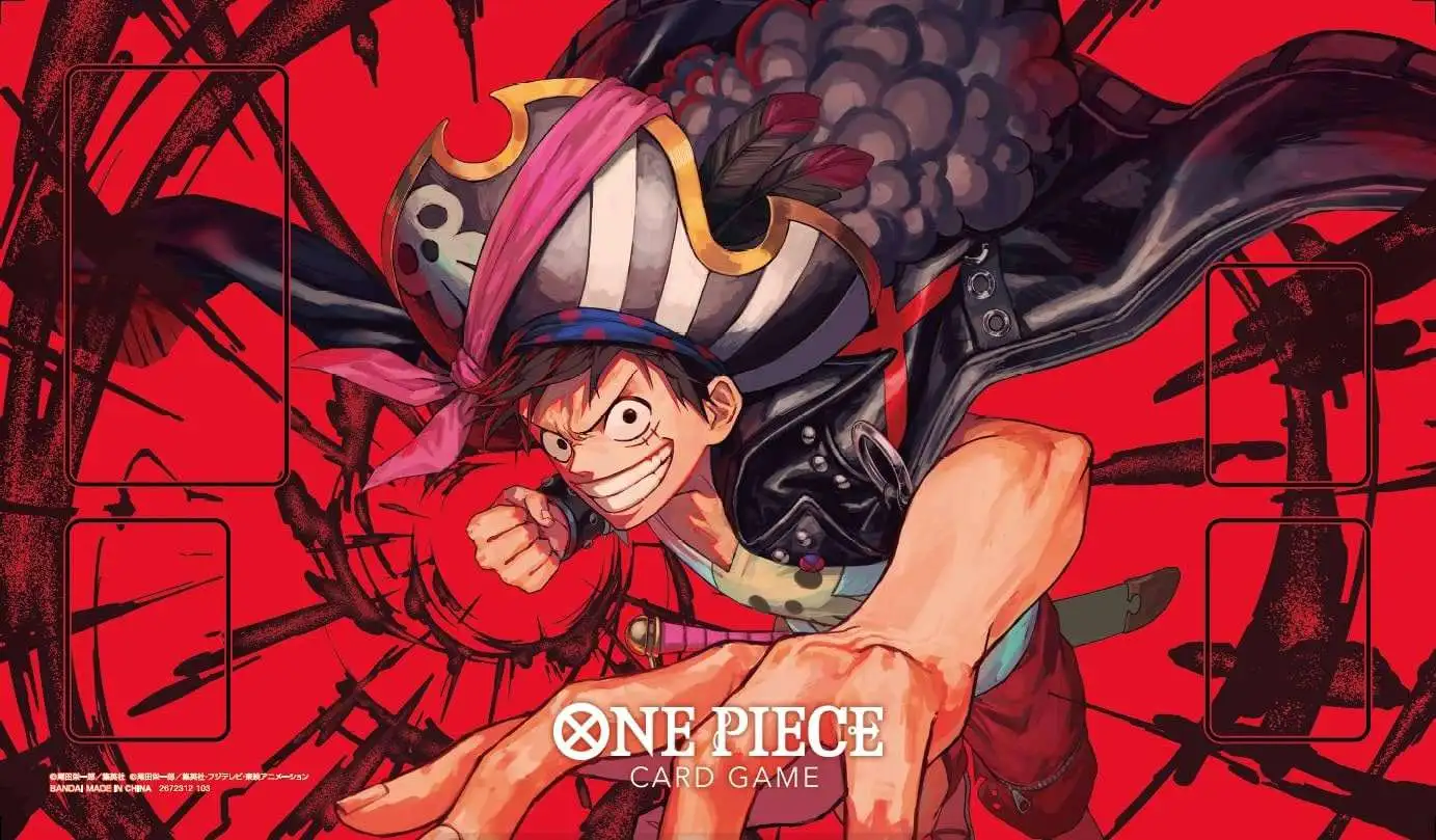 Bold red-and-black promotional playmat artwork for the One Piece Trading Card Game featuring Monkey D. Luffy charging forward in a pirate-inspired outfit with an oversized striped captain hat and flowing dark cape. The design incorporates dramatic brushstroke graphics, designated card placement zones, and high-contrast manga styling that give the accessory an intense competitive TCG aesthetic