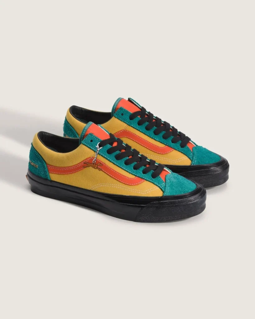 Colorful OTW by Vans Old Skool sneakers featuring mustard canvas panels, teal hairy suede overlays, coral side stripes and tongue accents, black laces and sole unit, finished with premium textured detailing and a dangling metallic charm against a neutral studio backdrop
