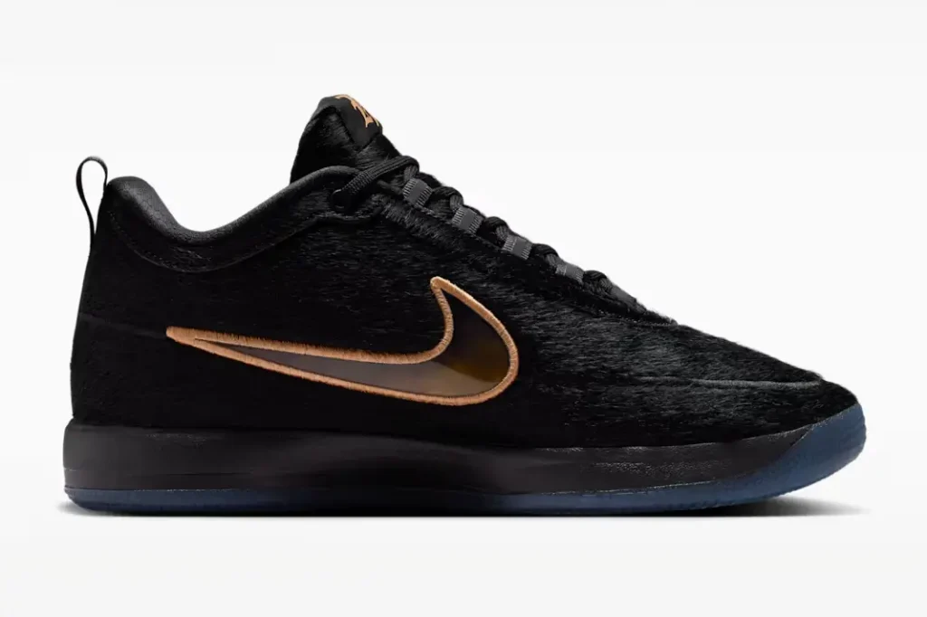 Side profile of the black furry Nike low-top sneaker showcasing glossy bronze Swoosh detailing, monochromatic midsole, and icy translucent outsole against a clean studio backdrop